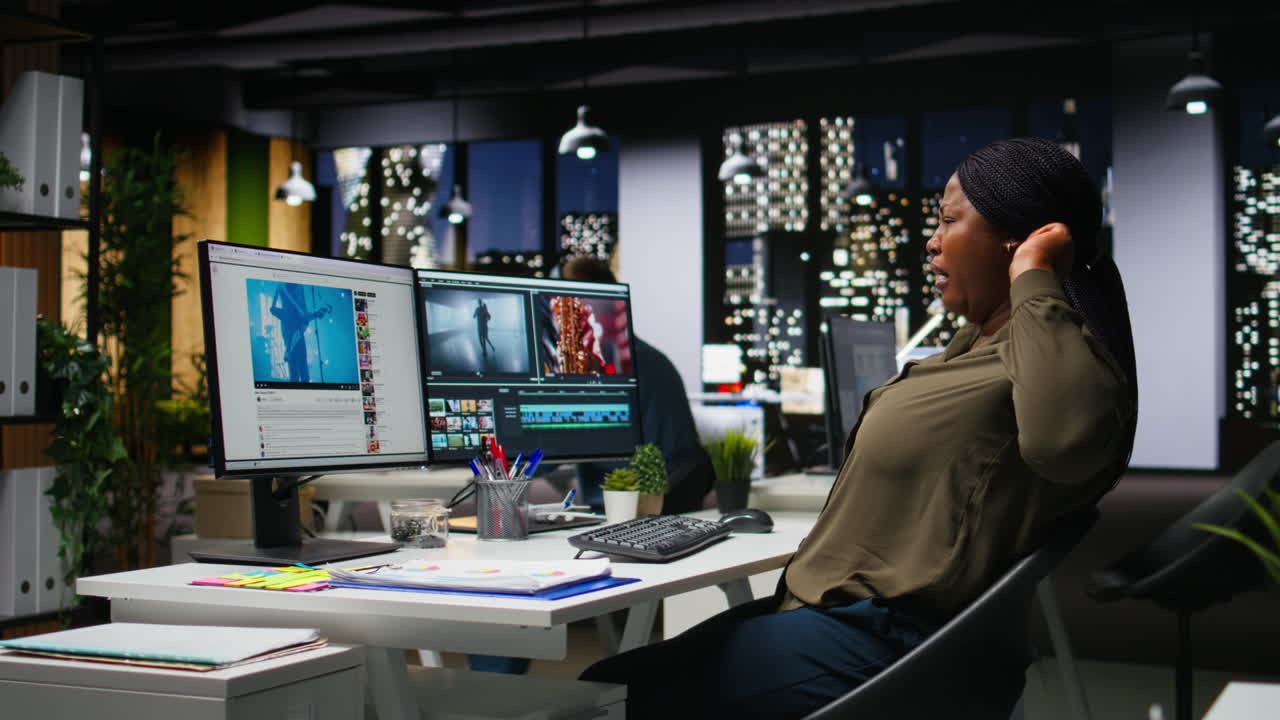 Woman film editor yawning and stretching her back on chair at night