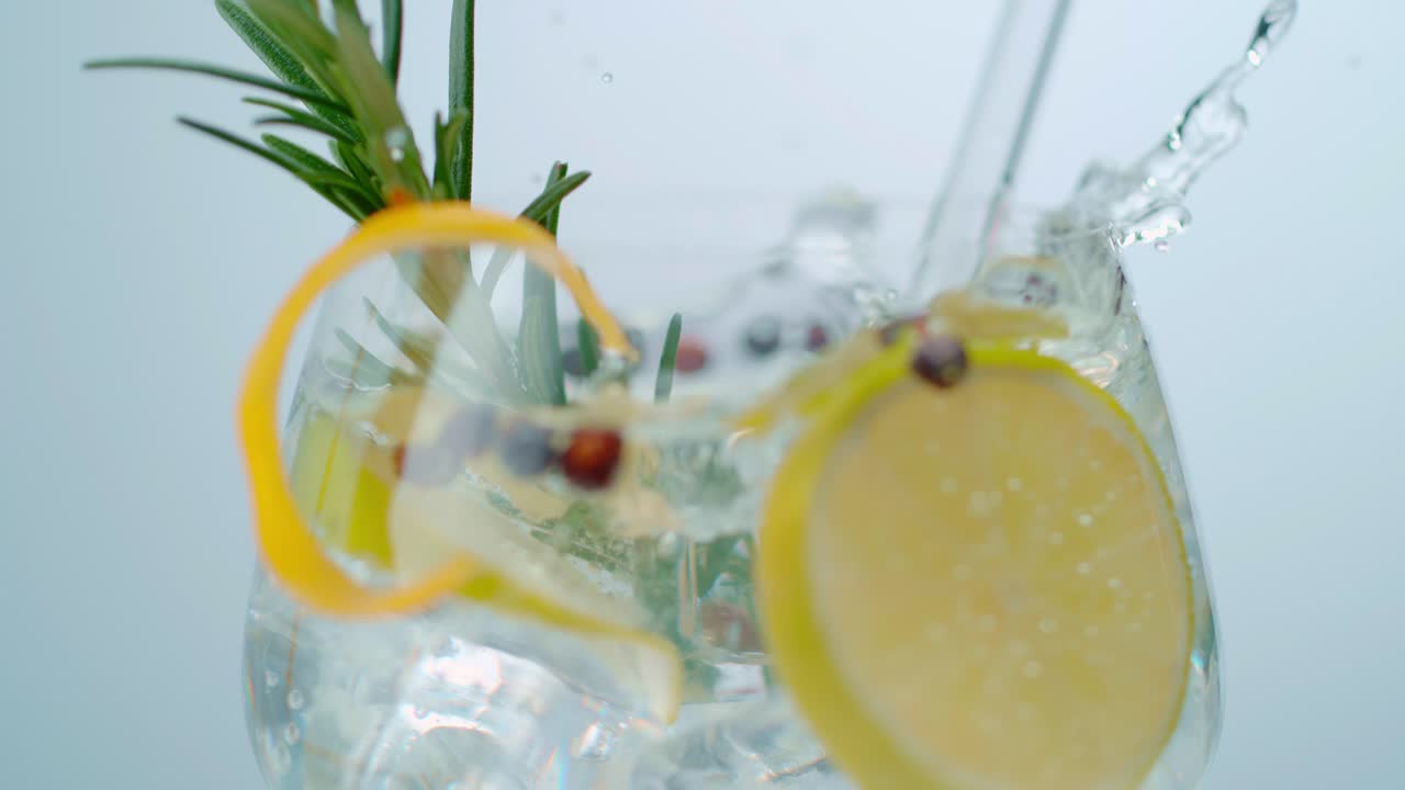 Cubetto di ghiaccio che crea uno spruzzo in un bicchiere pieno d'acqua e limone