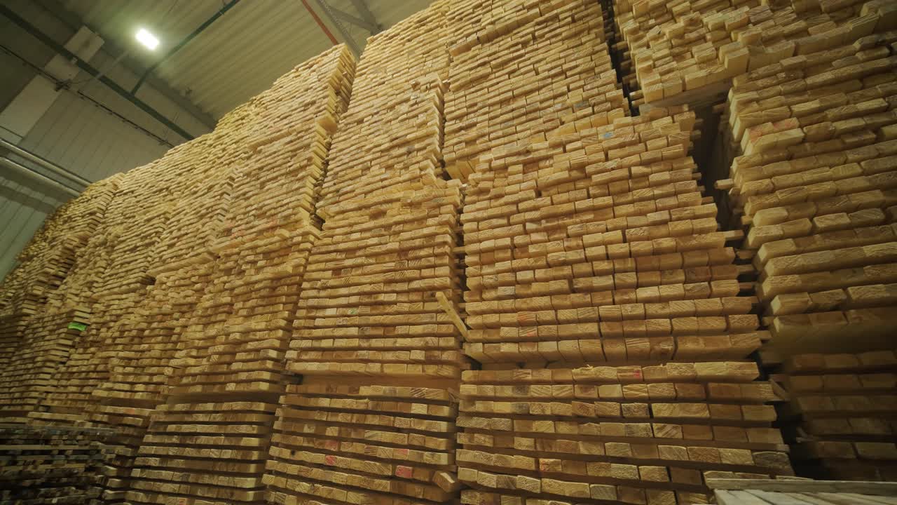 Tumpukan besar papan kayu olahan di gudang industri.