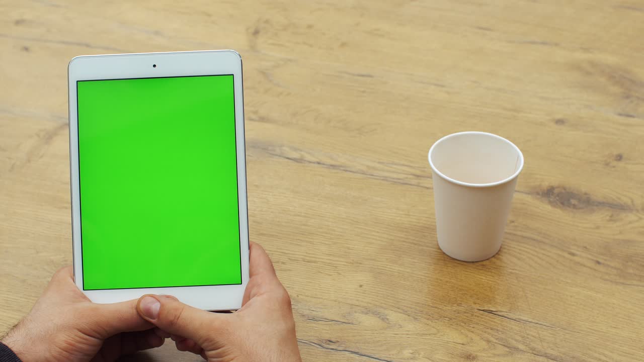 Tablet con schermo verde e tazza sul tavolo