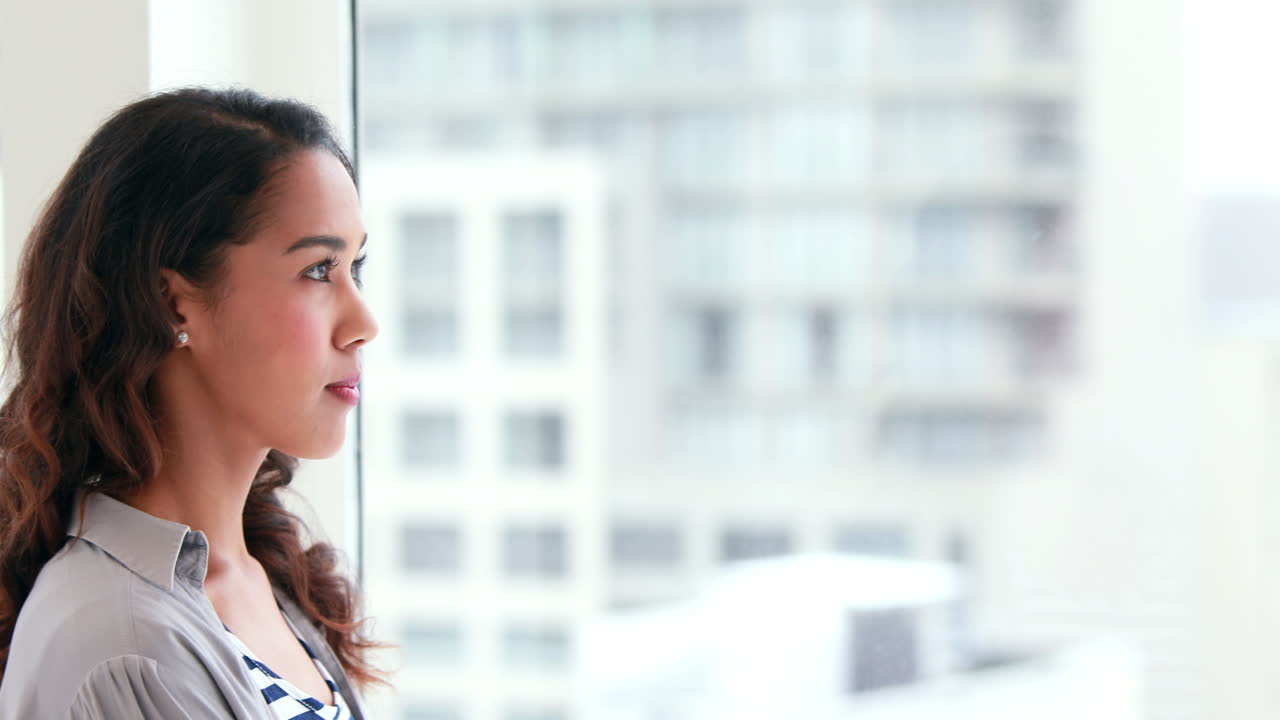una mujer de negocios pensativa mirando por las ventanas.