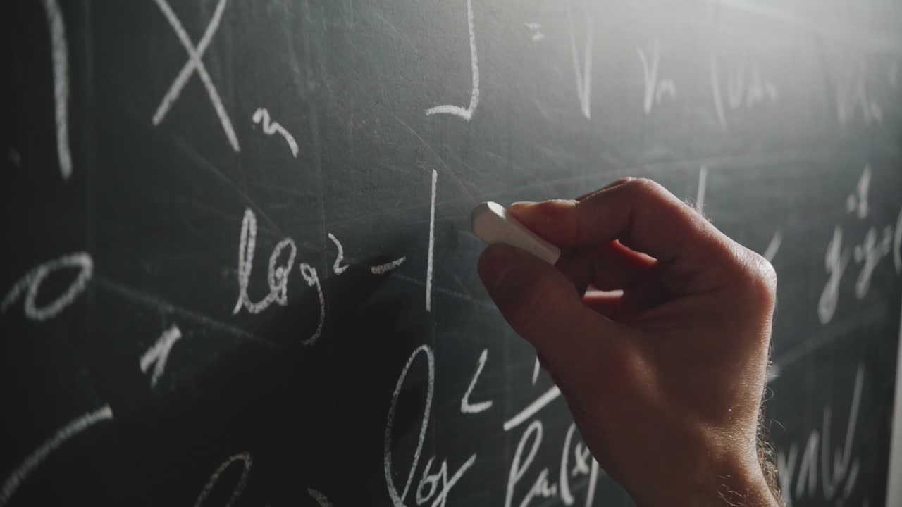 An extreme close-up, angled shot of a professor's hand writing a complex mathematical formula on a blackboard with chalk. A concept of science, education, and academia