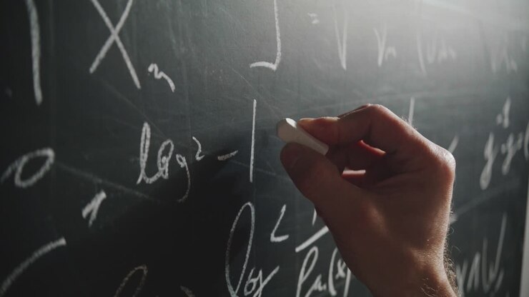 An extreme close-up, angled shot of a professor's hand writing a complex mathematical formula on a blackboard with chalk. A concept of science, education, and academia