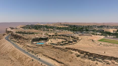 Borde-Del-Cráter-Ramon-Y-Ciudad-De-Mitzpe-Ramon-En-El-Horizonte,-Vista-Aérea