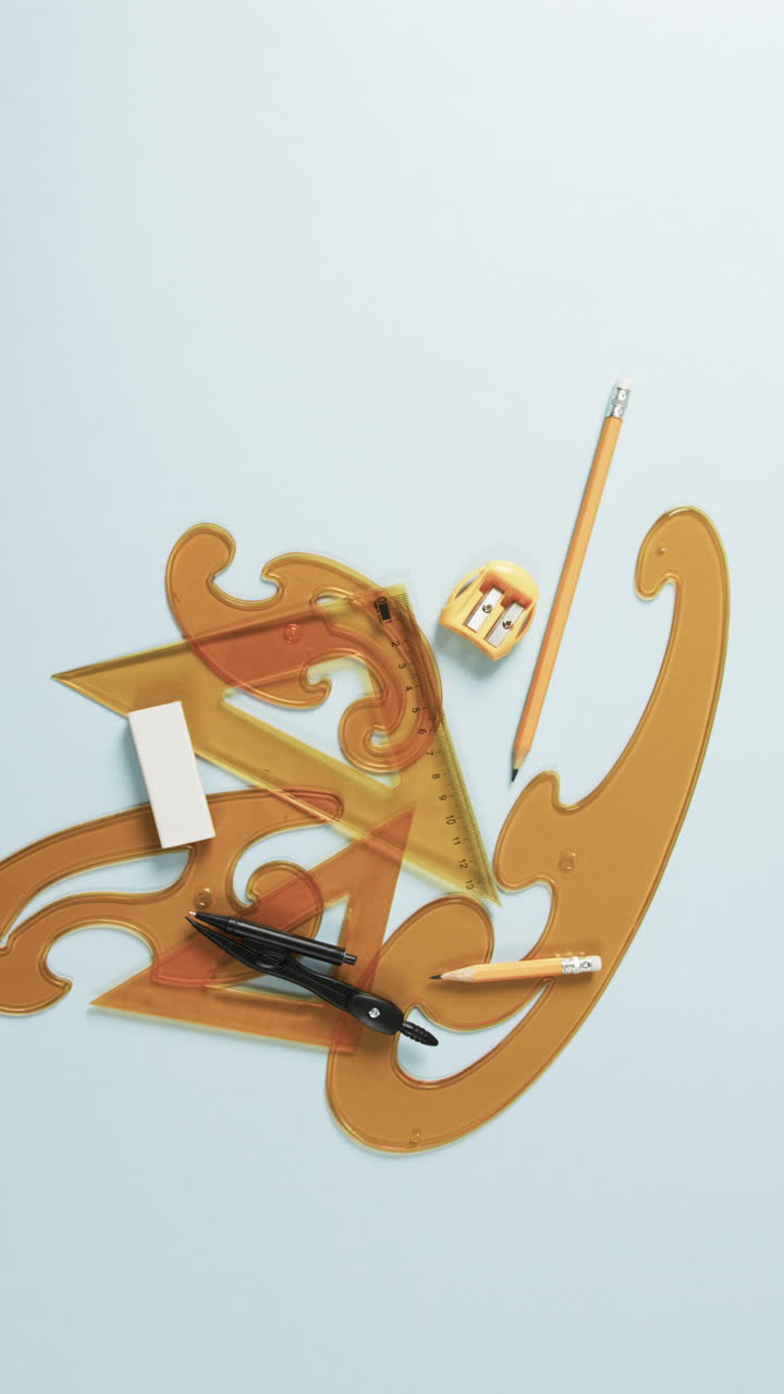 Vertical video of compass, pencil, sharpener, eraser and rulers on white background, slow motion