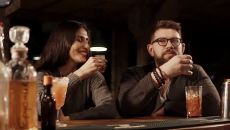 una pareja brindando bebidas en un bar.