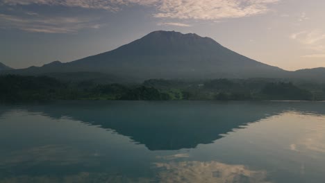 volcán monte agung durante el brumoso amanecer, reflejo de la piscina infinita en la superficie del agua, paisaje tropical