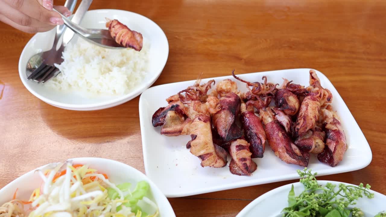 มือกำลังเสิร์ฟและกินข้าวไก่ย่าง