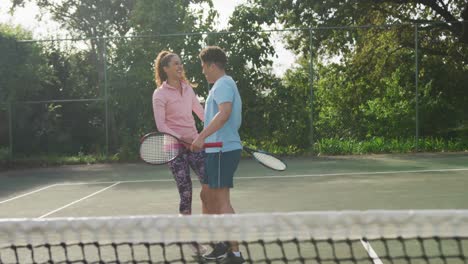 video de una feliz pareja biracial jugando al tenis en la cancha