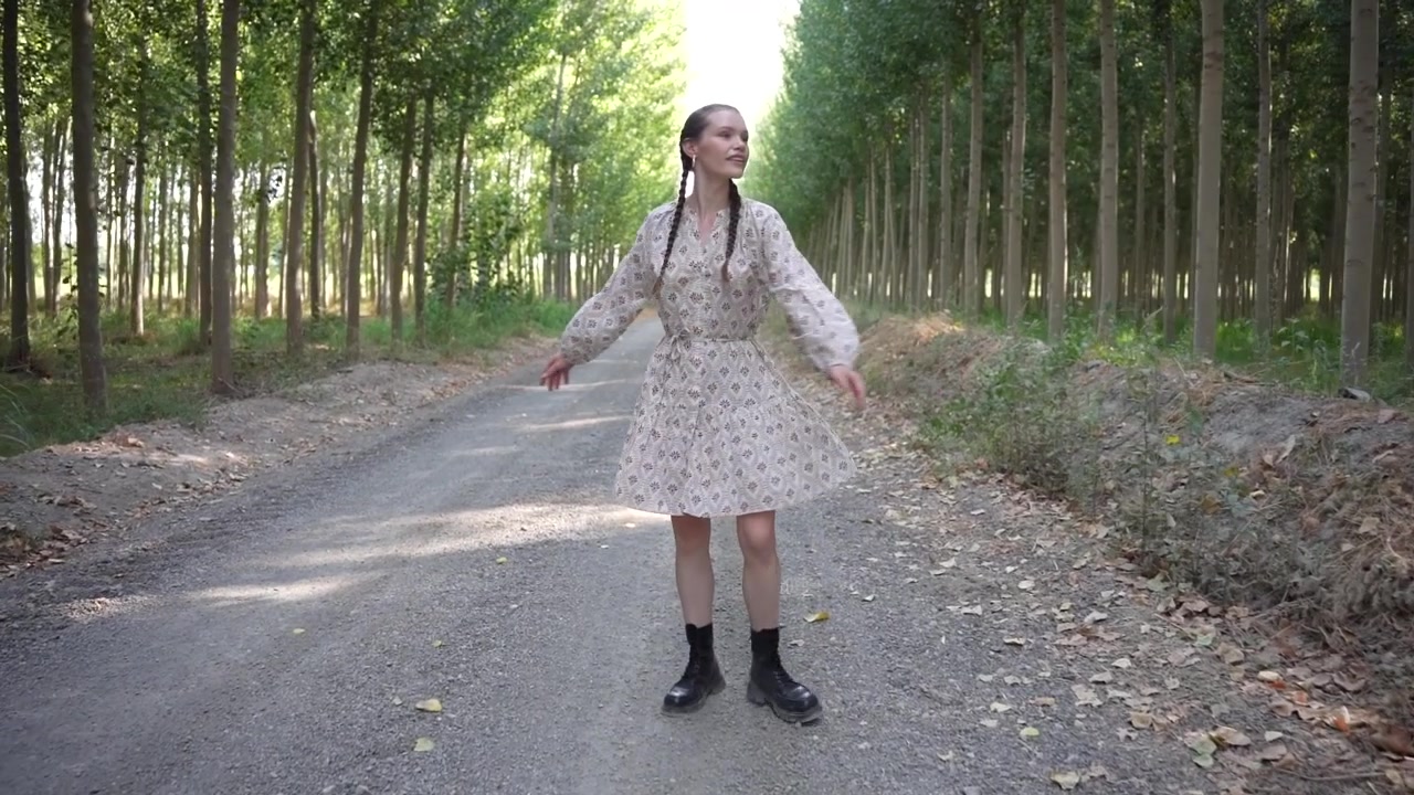 Una donna passeggia con grazia lungo un sentiero tranquillo con un vivace abito floreale.