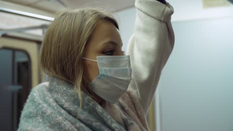 niña con una máscara médica de pie en un vagón del metro