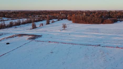 man walking dog in field in canada during winter at sunset
