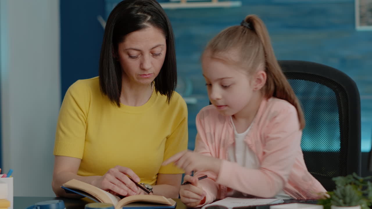 Skolejente som skriver i notatbok og sjekker bok for informasjon