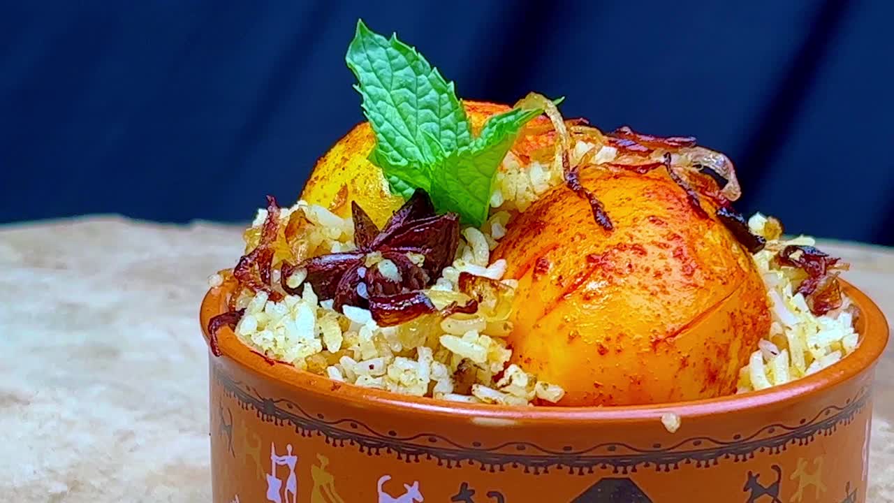 A bowl of biryani with roasted eggs on a rotating table