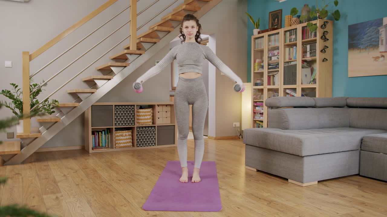 hembra morena joven sana ejerciendo hombros con pesas en el interior del hogar