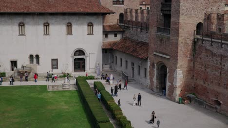 tourists walking at the courtyard of castelvecchio museum, restored palace in verona, italy