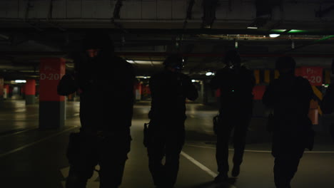 armed swat police officers examining area on underground parking in dark