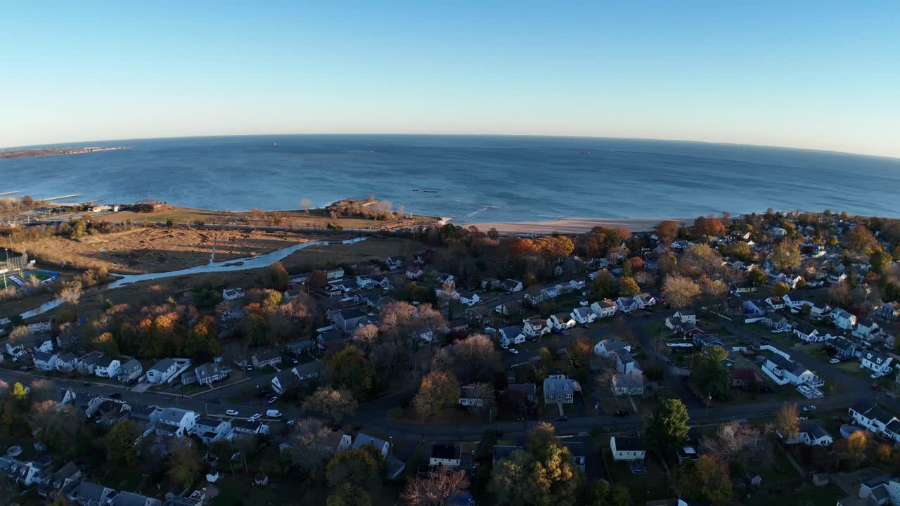 Vista aerea dell'alba su West Haven, Connecticut, che mostra case sulla costa, alberi autunnali e la costa di Long Island Sound sotto cieli limpidi e la luce dorata del mattino
