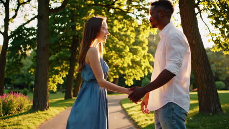 interracial couple holding hands and walking in a sunny park