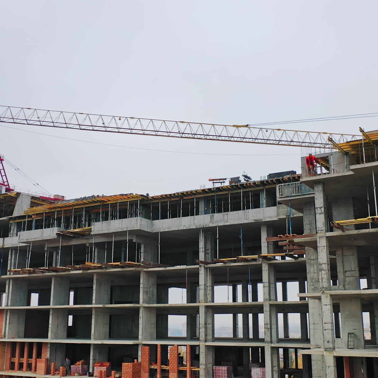 Drone view on a new construction site. Working process of construction the modern building on the background of two big cranes in the city.