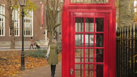 Cabina-Telefónica-Roja-Tradicional-En-Una-Calle-De-Londres-Durante-El-Otoño-En-Inglaterra,-Reino-Unido