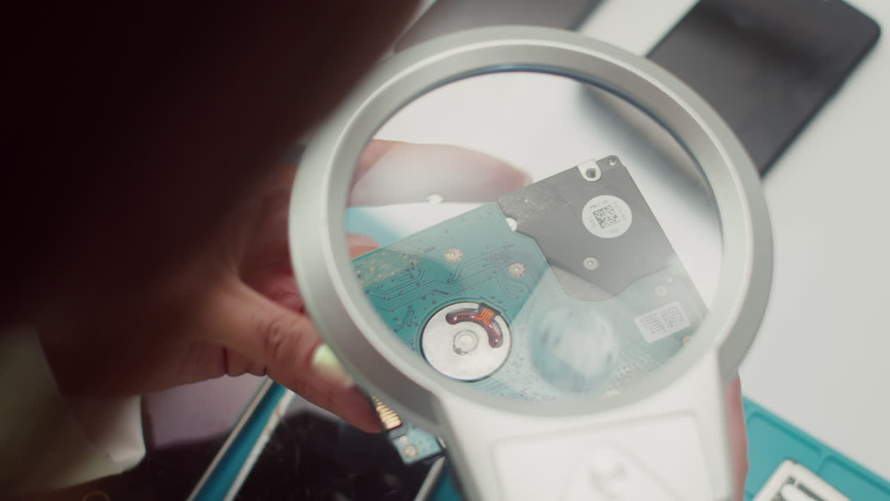 Technician Looking at Hard Drive through Magnifying Glass
