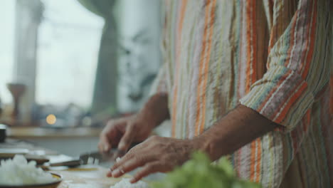 indian food blogger putting chopped onion into bowl on kitchen counter