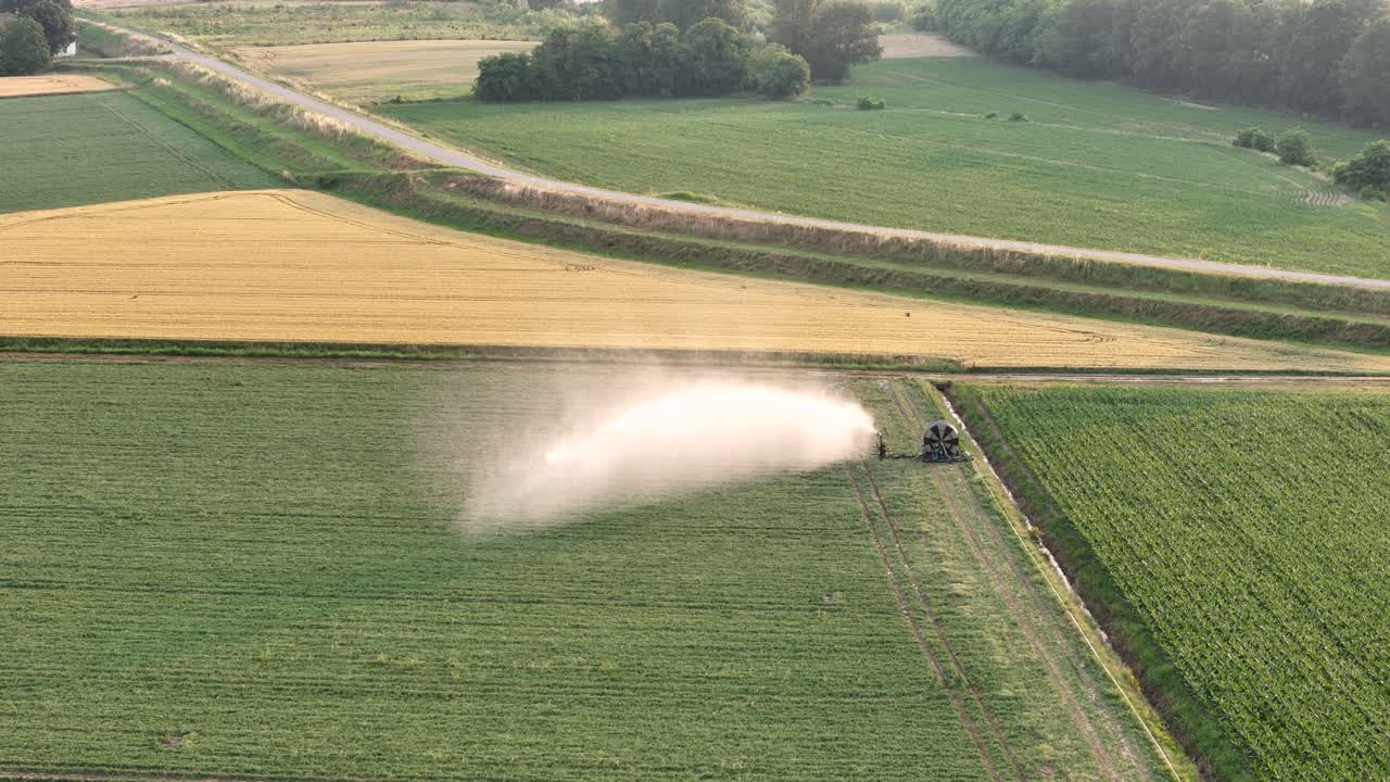 Vista aerea di un sistema di irrigazione automatizzato che spruzza acqua su coltivazioni di soia nella Pianura Padana, Italia, durante la primavera, garantendo idratazione e crescita adeguate