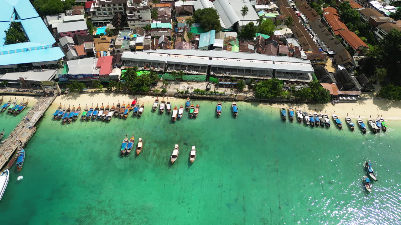 Aerial: Thailand's Iconic Long Tail Boats Lined Up By Tonsai Bay Pier in Koh Phi Phi Island, A Popular Travel Destination In Thailand