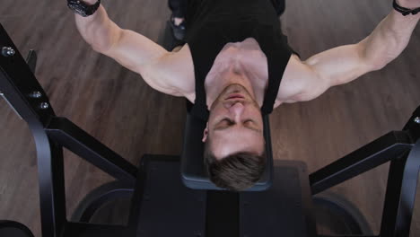 handsome guy training on a modern sports equipment. young athlete starts doing exercise on a simulator in gym. muscular man exercising in fitness center. top view.