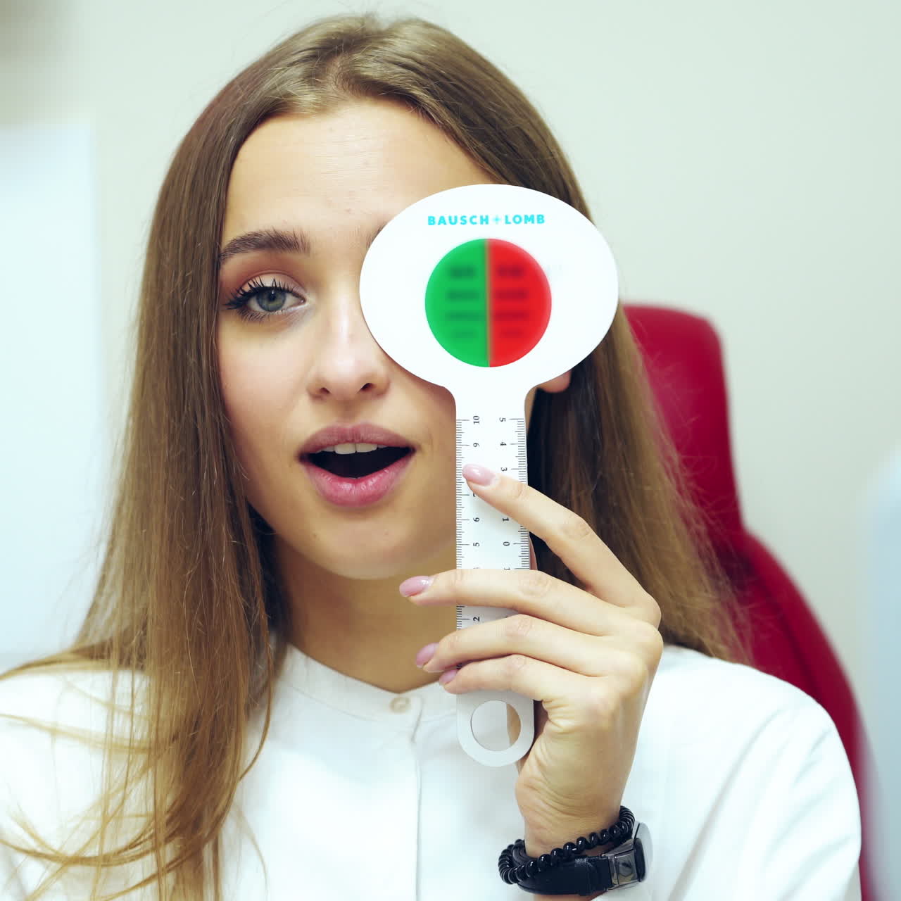 Young woman checking eyesight. Pretty girl doing vision test with one eye closed by occluder. Ophthalmology. Vision check-up.