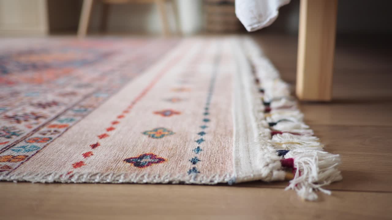 Primo piano di un tappeto decorato con frange su un pavimento in legno
