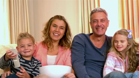 smiling family watching tv eating popcorn