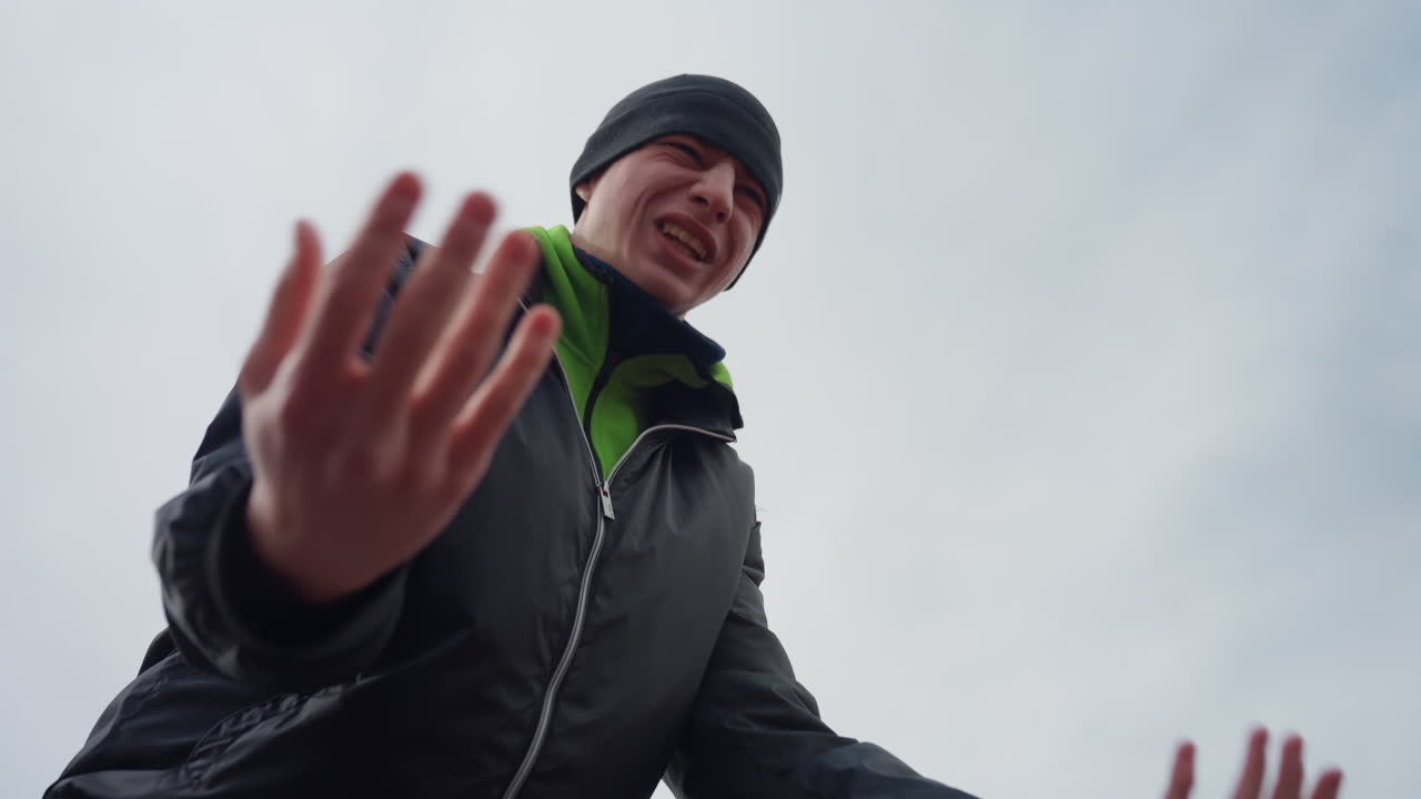 제스처를 취하는 축하하는 남자, 탁 트인 들판에서 소리 내는 즐거운 남자, 바람 부는 날에 제스처로 흥분을 표현하는 남자, 탁 트인 풍경 속에서 입을 벌리고 열정적으로 외치는 기뻐하는 남자