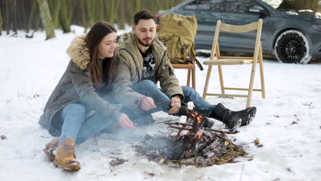 caucasian couple camping in a snowed forest.