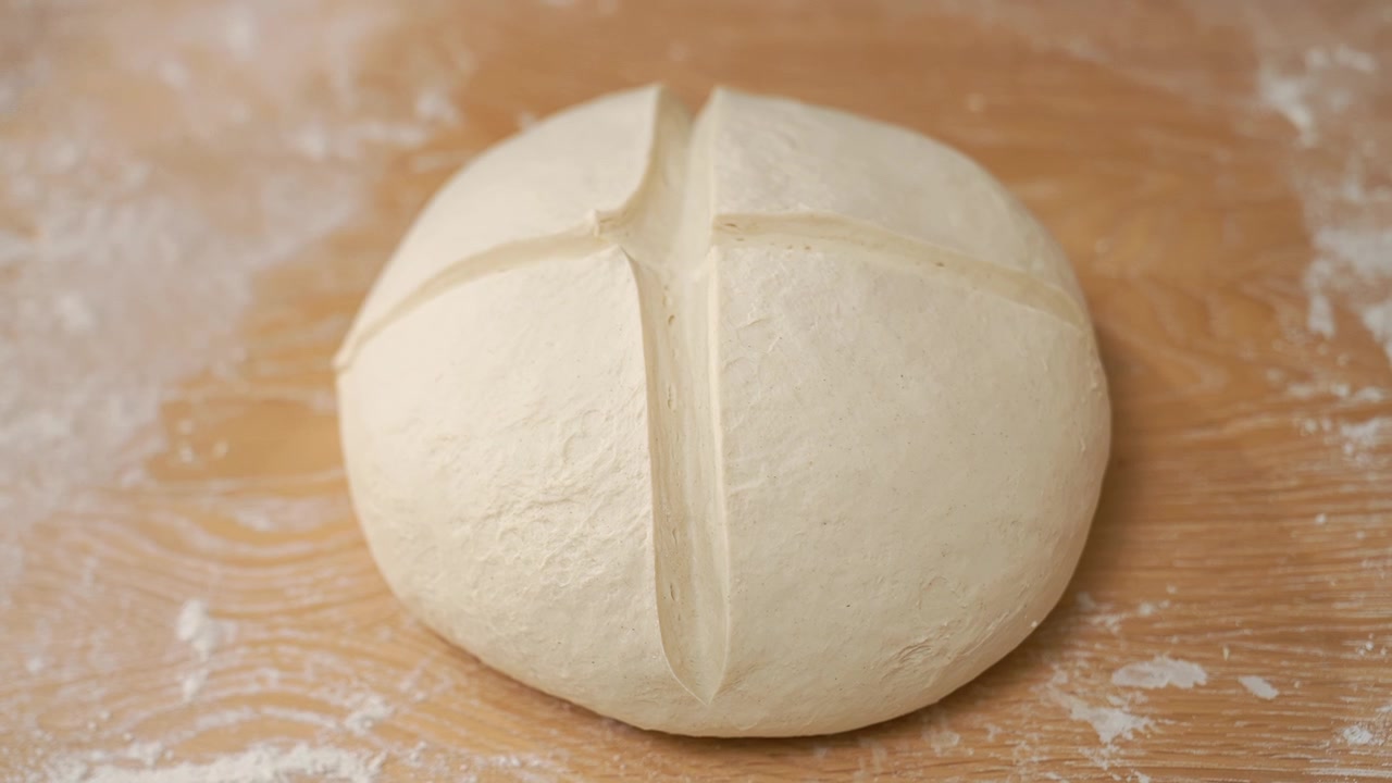Baker Scoring Round Dough with a Knife Before Baking