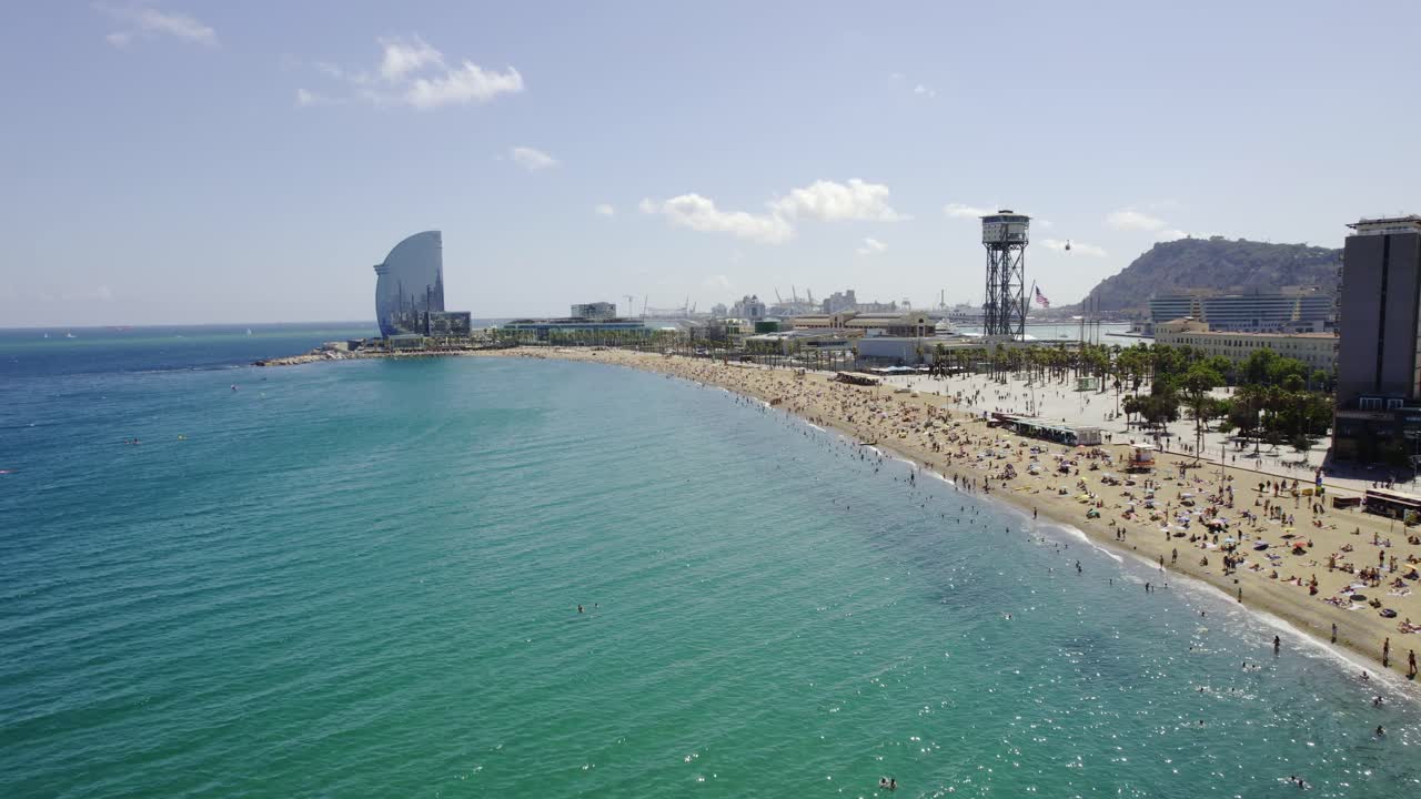 Vista aerea di una vivace spiaggia a Barcellona, con il W Hotel e una funivia.