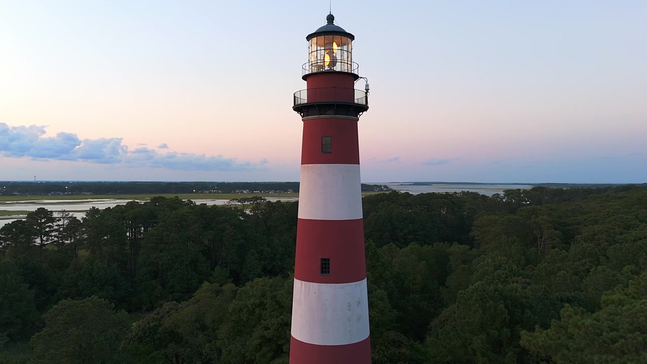 Faro di Assateague circondato da alberi verdi lussureggianti al tramonto in Virginia, Stati Uniti. - ripresa aerea