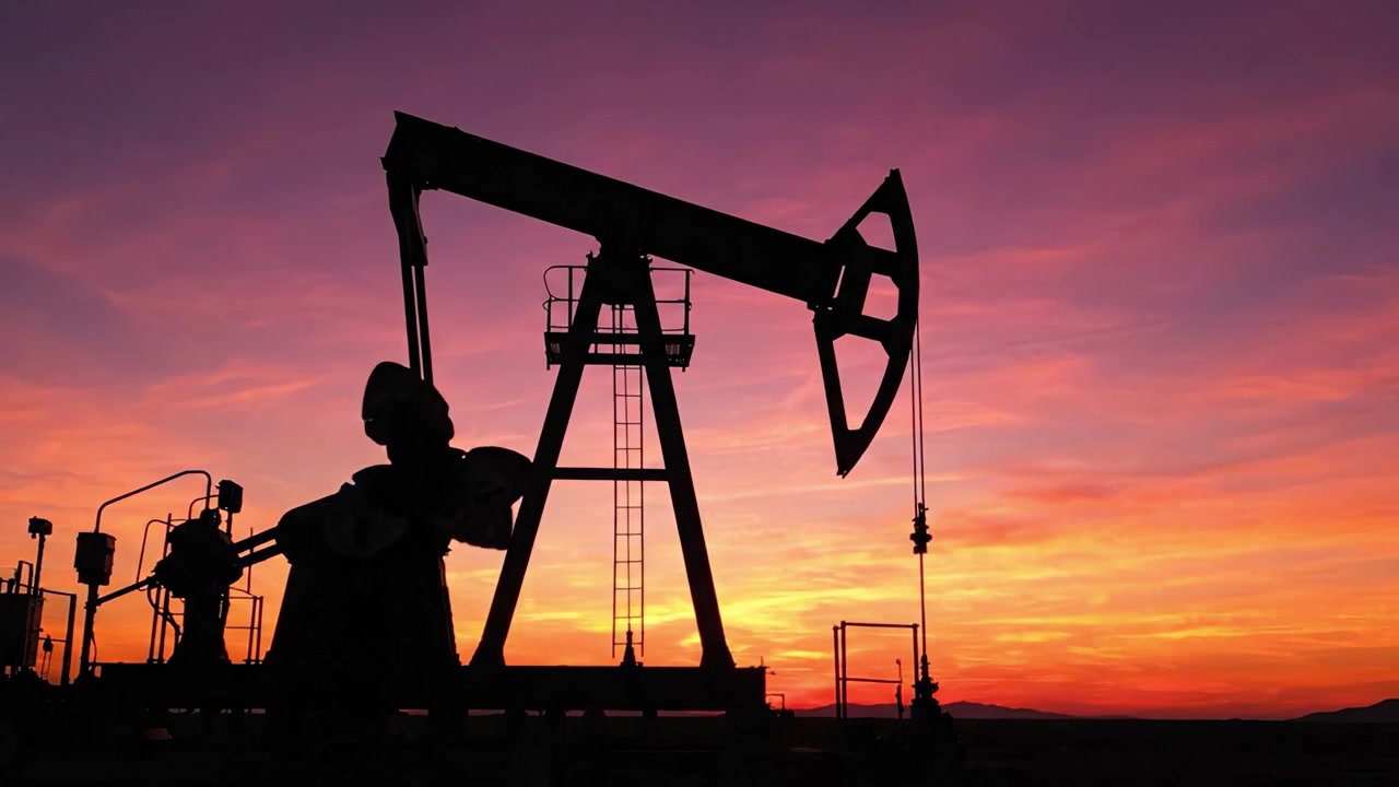 Silhouetted Oil Pump Jack Operating Against a Vibrant Sunset Sky, Symbolizing Energy Production and Natural Resource Extraction in the Modern Era