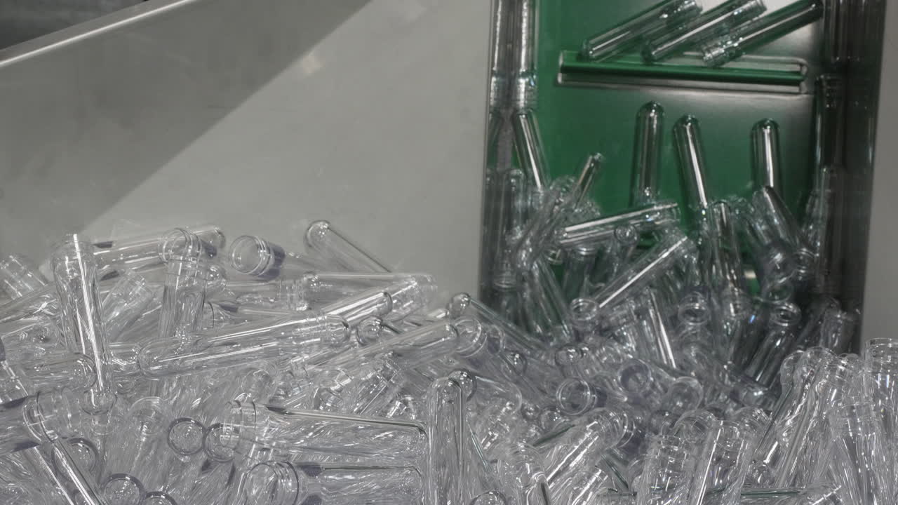 컨테이너에 쌓인 플라스틱 애완 동물 프리폼은 엘리베이터의 도움으로 또 다른 기술 프로세스에 들어가고 있습니다.