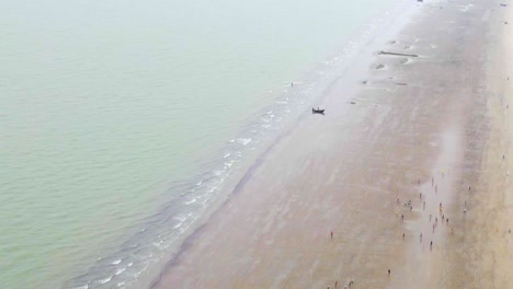 Luftaufnahme-Von-Menschen,-Die-Am-Strand-Von-Kuakata-Mit-Einem-Einsamen-Boot-In-Bangladesch-Fußball-Spielen