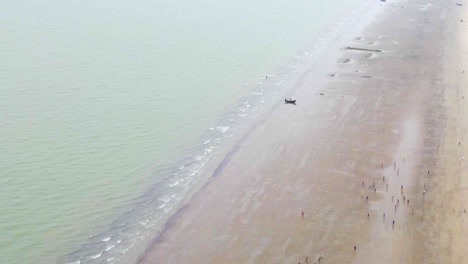 aerial view of people playing football at kuakata sea beach with lonely boat in bangladesh