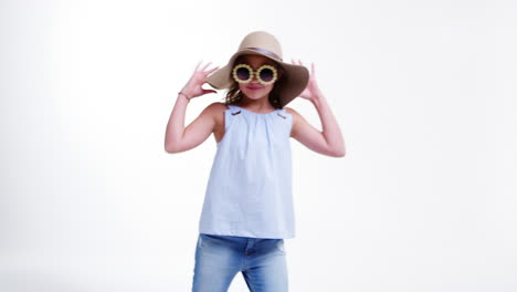 girl wearing hat and sunglasses poses against white background