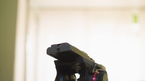 cameraman adjusting camera setup on tripod, focusing equipment for film production in studio, hand working with camera controls, preparing for video shoot in professional workspace