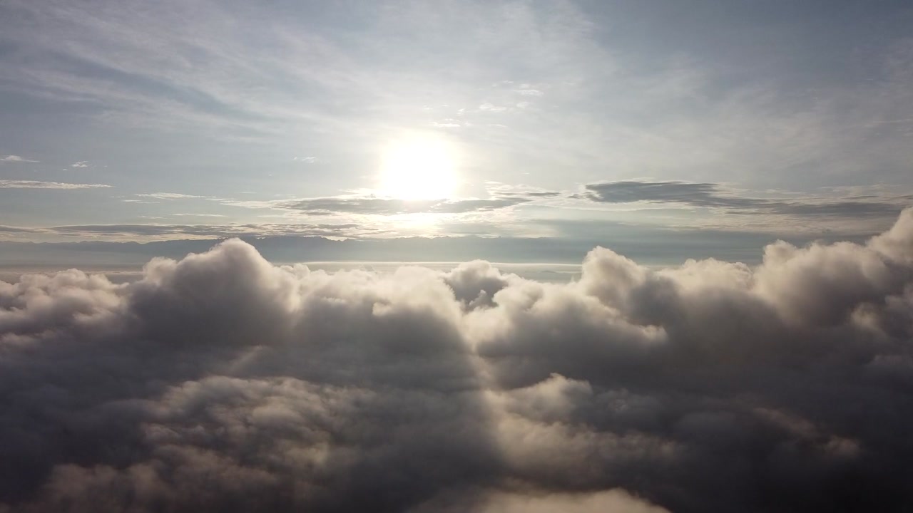 Stunning aerial footage captures the Drakensberg Mountains in South Africa bathed in sunlight above dense white clouds, showcasing breathtaking scenery from a lofty sky perspective.