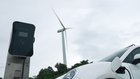 progressive combination of ev car, charging station and wind turbine.