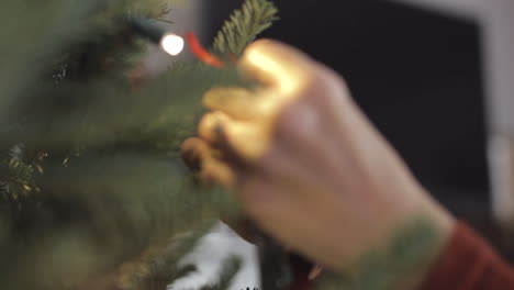 Static-Cropped-View-Of-A-Christmas-Tree-Being-Decorated-With-A-Hanging-Ornament-By-Female-Hands