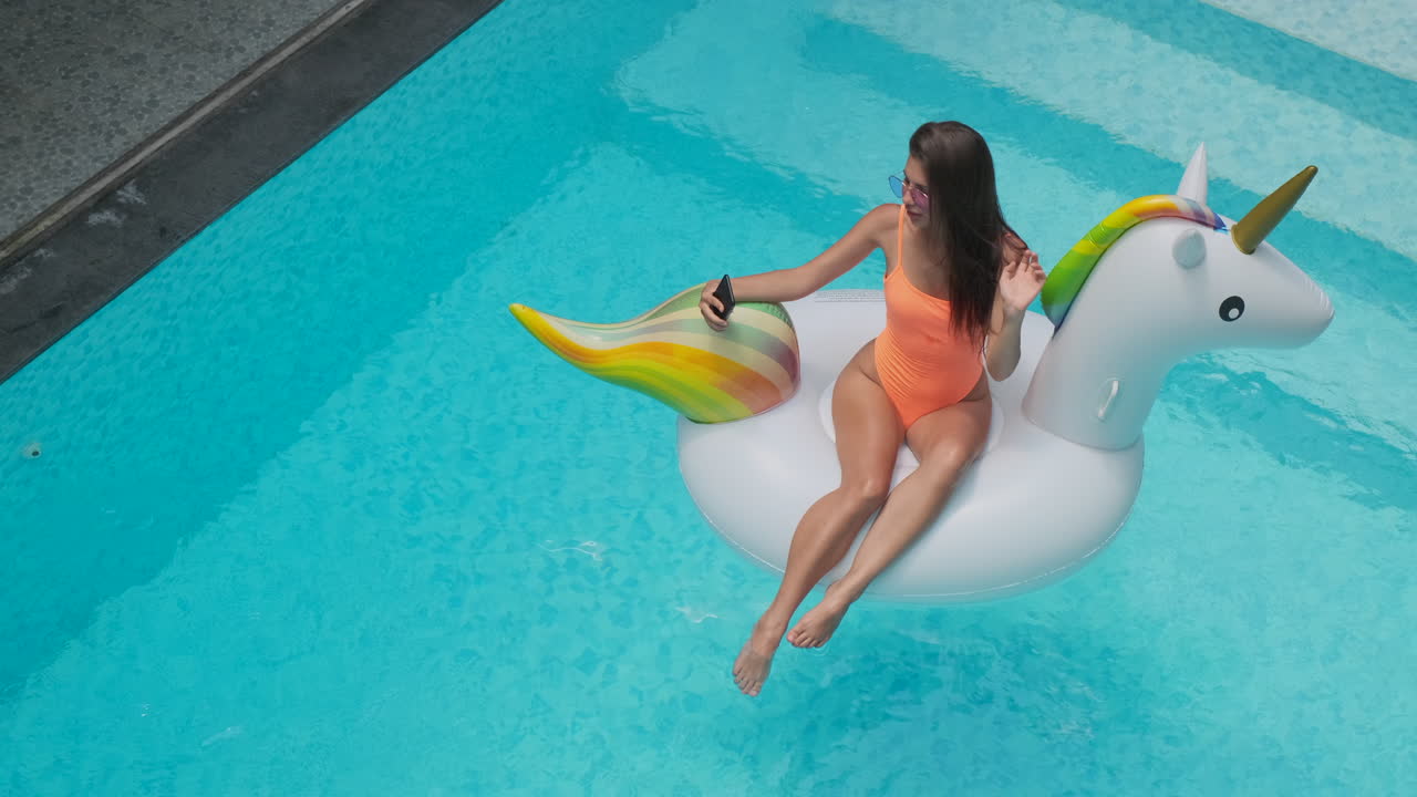 mujer divirtiéndose en una piscina en un unicornio inflable