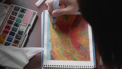 artist paints on sketchpad using a watercolor brush pen