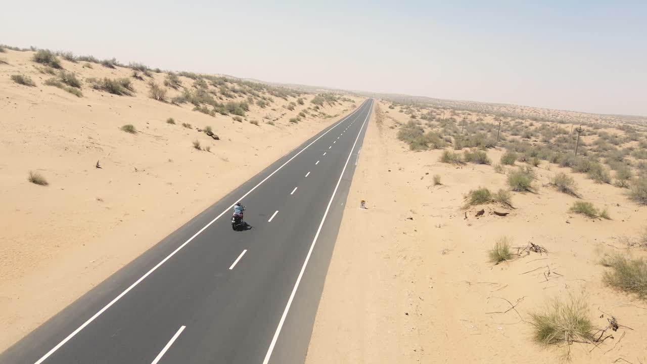 Aerial drone shot of a biker’s silhouette against the golden sands during late afternoon light.